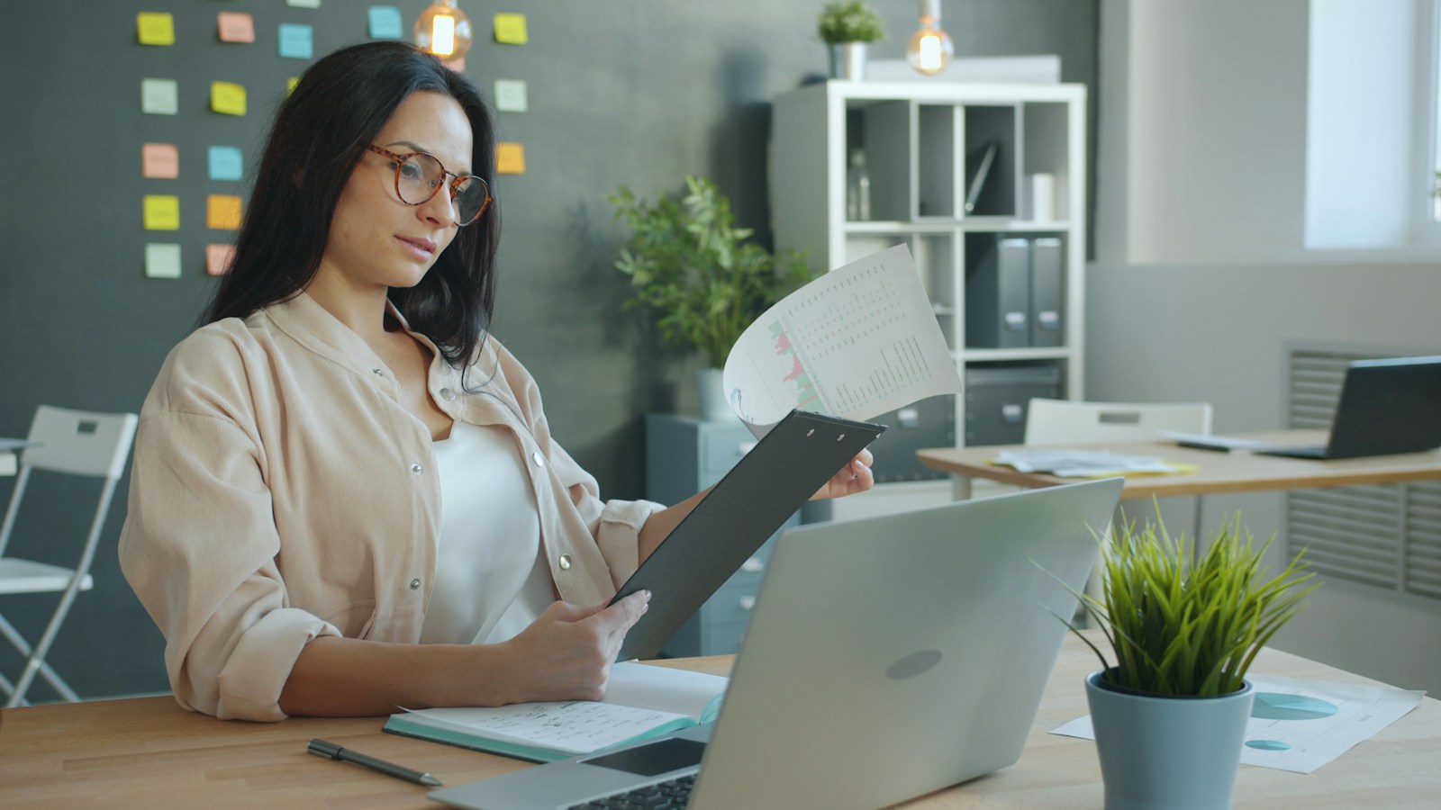 Office worker at a desk reviewing structured documents on a laptop